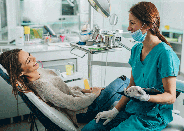 Stock photo of a dental hygienist talking chair side with her female patient.