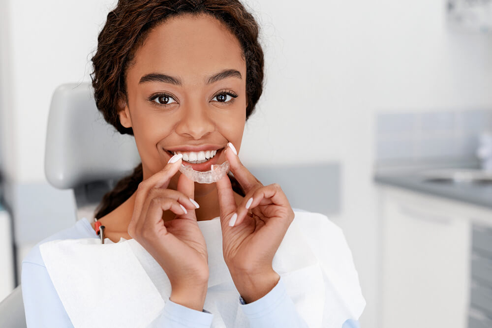 Smiling woman holding an invisalign aligners