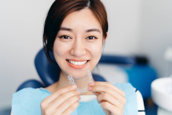 smiling woman holding invisalign